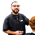 barbering student smiling and cutting someones hair