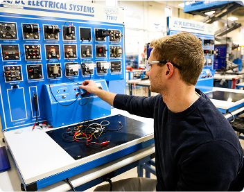 student adjusting large electrical equipment during class