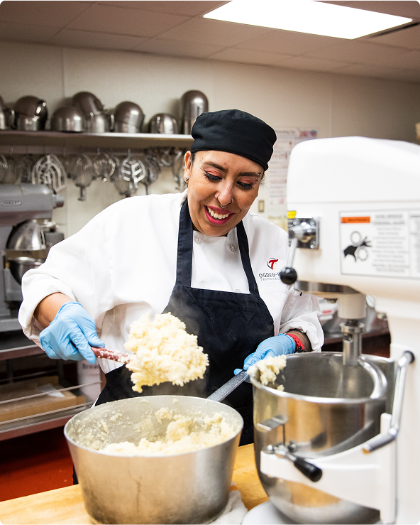 student mixing food in a mixer in the cooking school