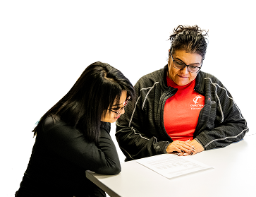 A financial aid advisor in an OTECH shirt helps a student review scholarship documents at a table, representing the personalized financial aid advising services available at Ogden-Weber Technical College