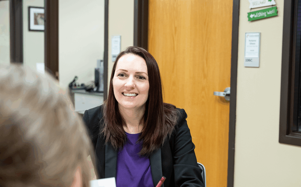 A financial aid advisor smiles while meeting with a student in an office, representing the scholarship advising and financial assistance available to OTECH students