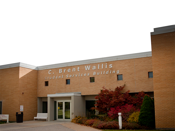 Exterior of the C. Brent Wallis Student Services Building at OTECH's main campus, a brick building surrounded by colorful autumn foliage, where students can access job coaching and student success services
