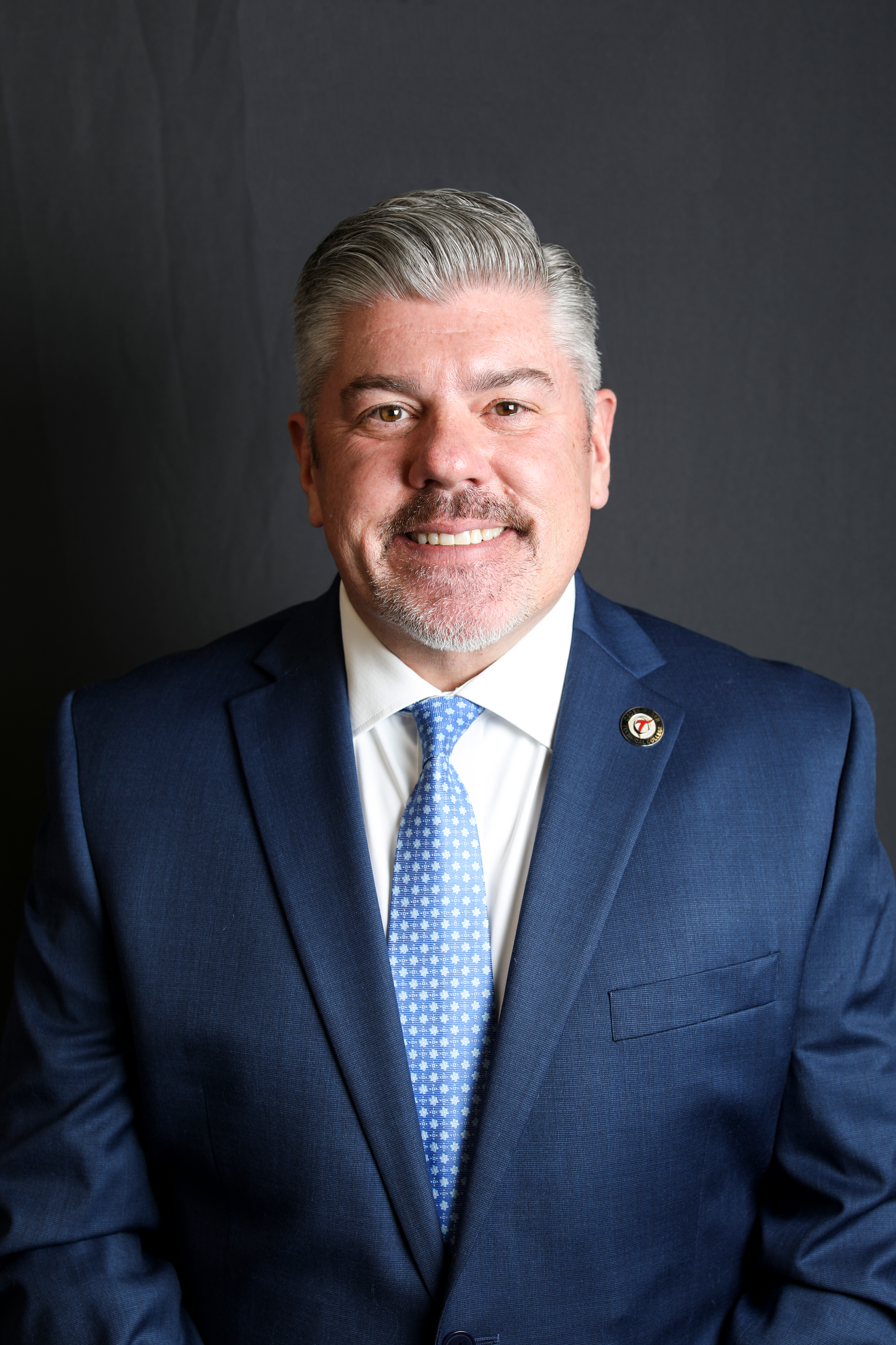 Jim Taggart, professional headshot with silver hair against a dark background