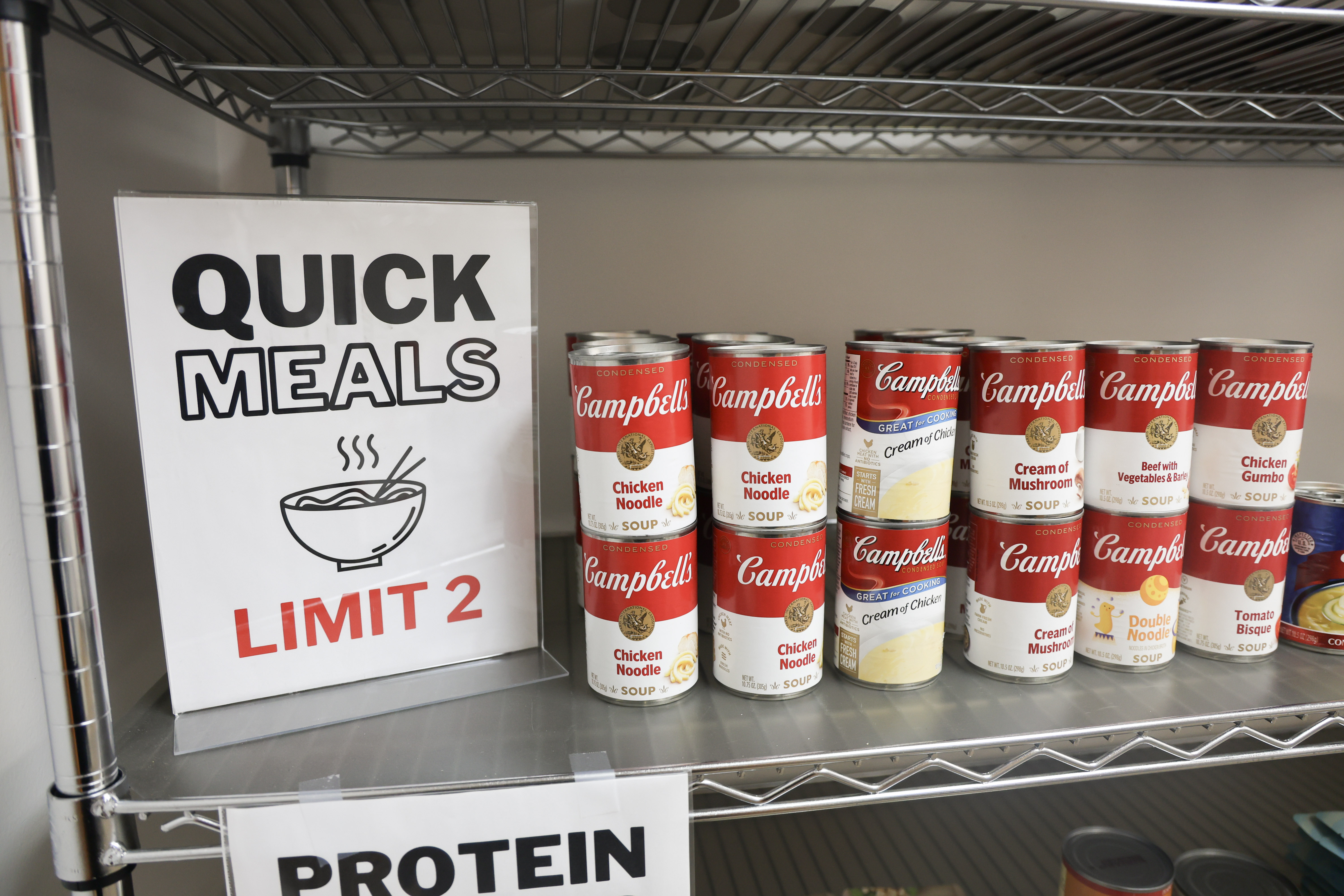 Student Success Center food pantry with rows of Campbell's soup cans and a Quick Meals limit 2 sign